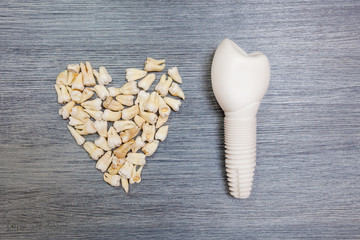 Torn teeth are laid out by a heart lie on the table. Model of dental implant. Teeth of people