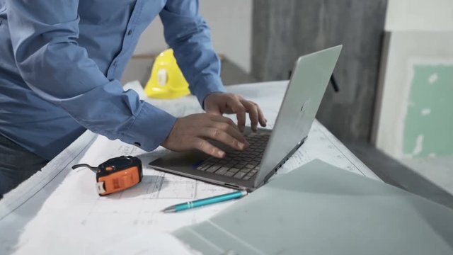 Man working with laptop standing by table at new home
