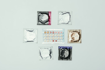 top view of arranged condoms and contraceptive pills isolated on grey
