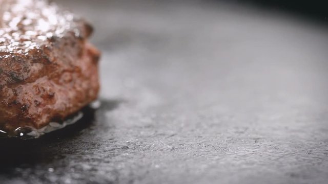 Cooking hamburger patty on hot skillet macro close up with smoke and grease in slow motion.