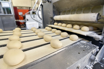 frische Brotlaiber auf dem Fliessband einer Großbäckerei - industrielle Lebensmittelherstellung...