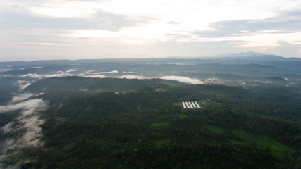 Aerial view of forest, mountains with fog, clouds at sunset on Bali,Indonesia. Tropical rainforest,...