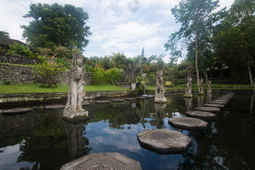 Fototapeta na wymiar Hindu Balinese Water Palace Tirta Gangga with statues of the gods, fountains on Bali island, Indonesia. Tirta Gangga the former royal water palace is a maze of pools and fountains surrounded by a lush