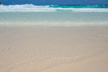 Turquoise waves pushing crystal clear water on to the almost white sandy beach at Batok Bay on Ko Racha Yai. Racha Island is off the southeastern coast of Phuket, Thailand.