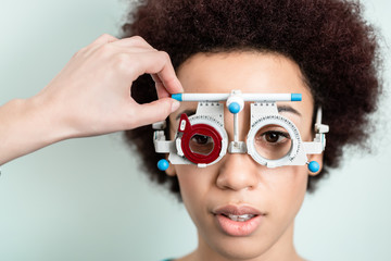 Woman having eyesight test with phoropter for new glasses at optician or eye doctor specialist