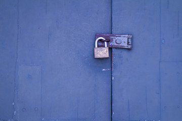 Old rusty padlock in locked status on blue wooden door with copy space for text input