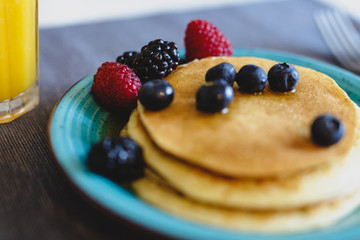 Pancakes with wild berries and maple syrup. Selective focus on the berries