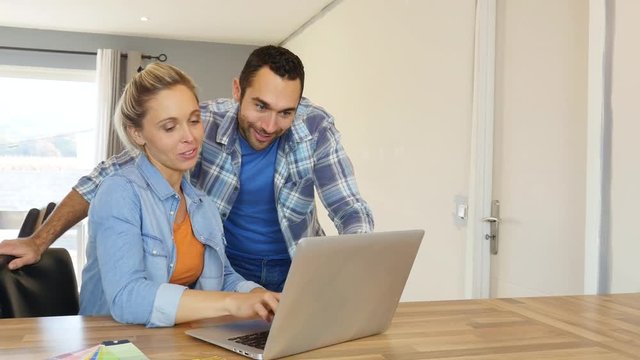 cheerful young couple buying and shopping on internet with a laptop computer