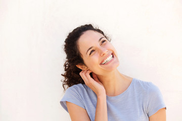 Horizontal portrait of young woman smiling against white wall