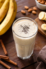 Glass of banana smoothie with chia seeds on wooden table. Top view, selective focus
