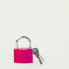 Red metal lock with a pattern in the form of a heart and keys on a white background.