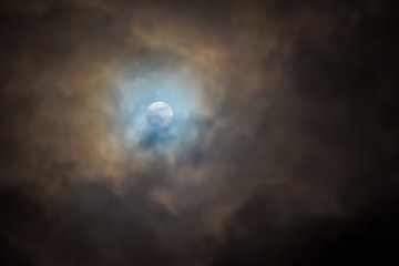 Fototapeta na wymiar full bright moon in a dark sky, covered with clouds