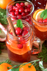 Punch with cranberries and orange decorated with mint and a stick of cinnamon in glass vessels