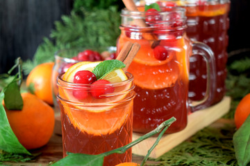 Punch with cranberries and orange decorated with mint and a stick of cinnamon in glass vessels