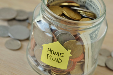 Coins and bills in a jar with label Home Fund - Financial concept