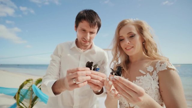 The newlyweds, groom and bride, together in their hands are beautifully painted butterflies. A fabulous and magical moment of the wedding day.