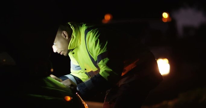 4k, African American male mechanic working on a broken down car late at night.
