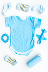 Blue set for newborn boy. Baby bodysuit, socks, airplan toy and powder on white background top view