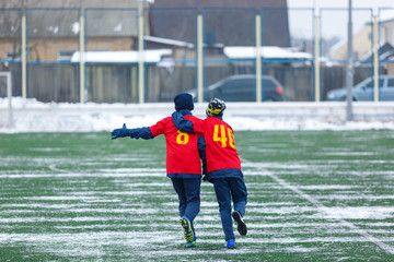 Obraz premium Young kids football tournament - children play match on soccer field during the snow falling