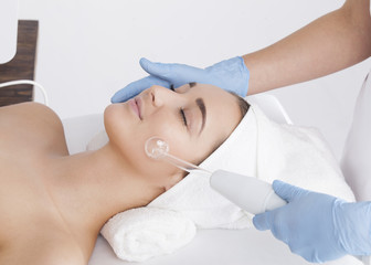 The beautician makes a rejuvenating treatment using specialized equipment