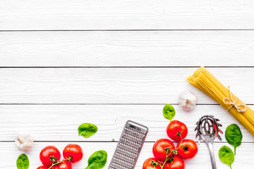 Cook spaghetti with tomatoes, garlic, basil. Italian recipe. White wooden background top view copy space