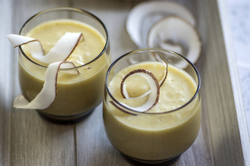 Pineapple smoothie with bananas, oatmeals and coconut milk, decorated with coconut chips, wooden breakfast tray