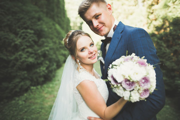 Newly married couple running and jumping in park while holding hands