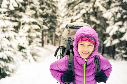Happy woman walking in winter forest with backpack