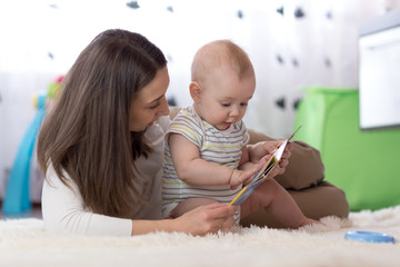 Mother showing images in a book to her cute baby son at home