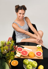 Obraz na płótnie Canvas Healthy eating. Vertical portrait of a beautiful young woman at the table. Sliced fruit on the table