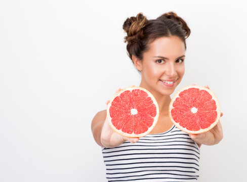 Freshness and vivacity. Young cheerful woman showing red halves of grapefruit