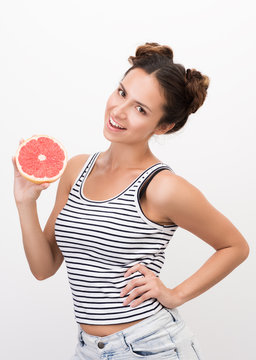 Joyful young woman holding a grapefruit. Striped tank top. Healthy, natural food