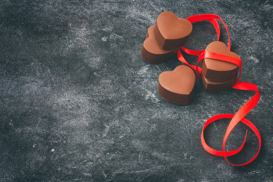 Valentine`s Day greeting card, milk chocolate heart shape, red silk ribbon