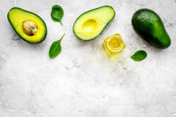 Vegetable oil as cosmetics. Avocado oil in bottles near sliced avocado on grey background top view copy space