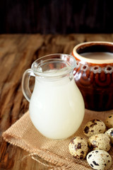 Milk whey, quail eggs and a clay pot on a wooden background. Farm products