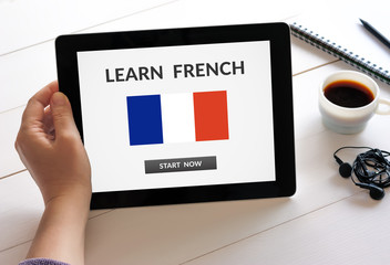 Hand holding digital tablet computer with learn French concept on screen. All screen content is...