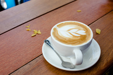 Latte coffee art in white cup on wood table outdoor