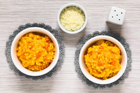 Fresh homemade carrot risotto made with pureed carrot and roasted carrot pieces, served in bowls, photographed overhead with natural light (Selective Focus, Focus on the top of the risotto)
