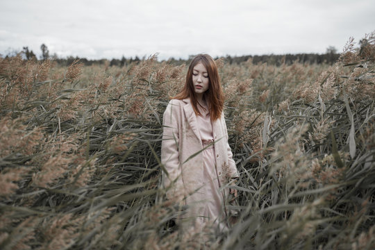 Stylish young woman standing in windy marsh grass