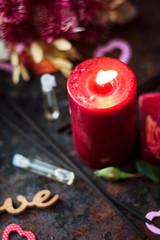 Flaming candle and small perfume bottle on black surface.