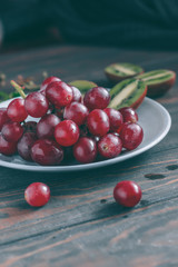 Red grapes on a gray plate and wooden table 