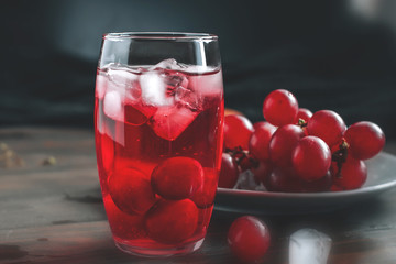 Fresh grape juice with ice and red grapes on a wooden table