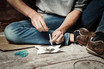 A drug addict makes a cigarette with marijuana. The concept of drug abuse and traffic