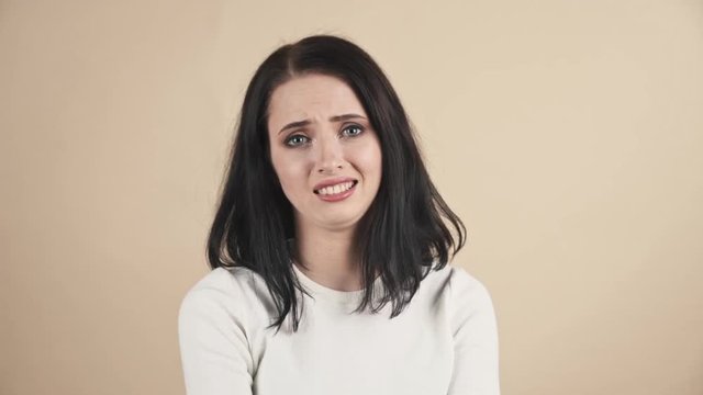 a young beautiful cute brunette on a beige orange background showing  oops, Oh, accidentally, not guilty emotions