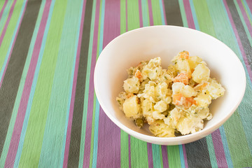 Potato salad inside a white bowl.