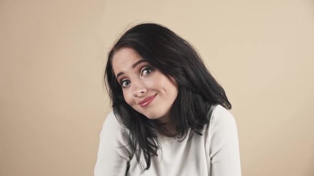 a young beautiful cute brunette on a beige orange background showing  oops, Oh, accidentally, not guilty emotions