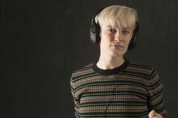 Young blonde woman wearing headphones and enjoying the music.