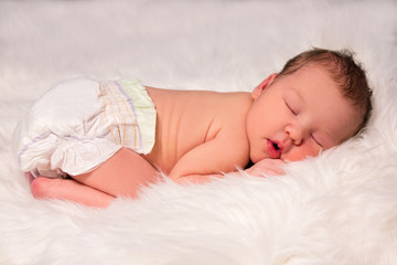 cute sleeping newborn baby in diaper over white blanket © Di Studio