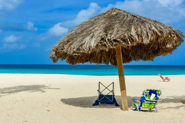 Sunbeds and parasol on the white sand of Palm Beach in Aruba.