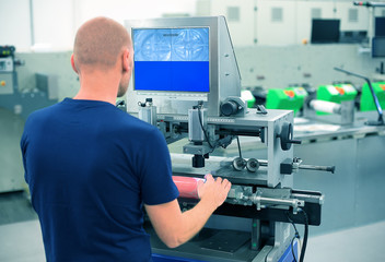 Worker in a printing and press center uses plate mounting machine to attach polymer relief plate on...